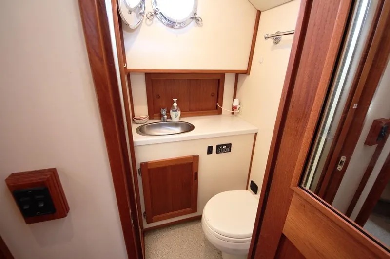 Egret Yacht Photos Pics 2005 Nordic Tug 37 Flybridge bathroom with sink, toilet, and wooden cabinetry.