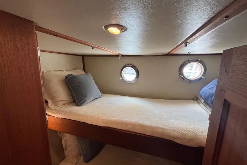 Egret Yacht Photos Pics Cozy cabin interior of 2005 Nordic Tug 37 Flybridge with porthole windows and bedding.
