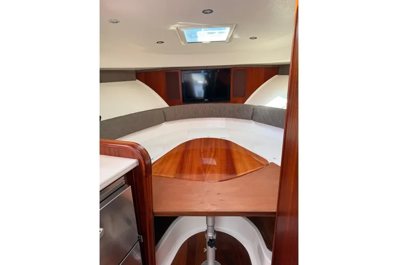  Yacht Photos Pics 2015 Pursuit OS 385 Offshore cabin interior with wood table and seating area.
