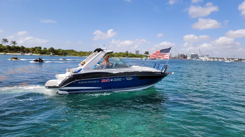  Yacht Photos Pics 2019 Monterey 295 Sport Yacht cruising on clear blue water with American flag.
