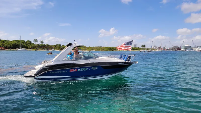  Yacht Photos Pics 2019 Monterey 295 Sport Yacht cruising on clear blue water with American flag.