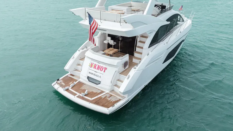 Why Knot Yacht Photos Pics 2020 Sunseeker 52 Manhattan yacht on turquoise water, rear view with American flag.