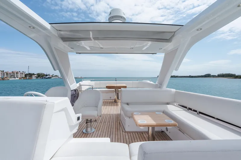 Why Knot Yacht Photos Pics Luxurious Sunseeker 52 Manhattan yacht interior with white seating, wooden deck, and ocean view.