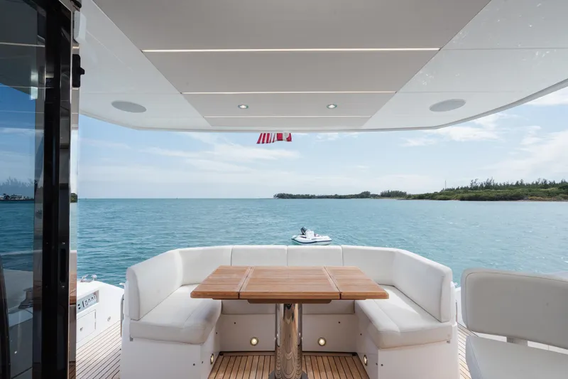 Why Knot Yacht Photos Pics Luxurious Sunseeker 52 Manhattan yacht deck with ocean view, featuring elegant seating and table.