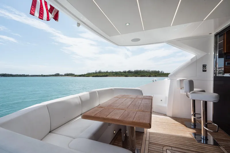 Why Knot Yacht Photos Pics Luxurious Sunseeker 52 Manhattan yacht deck with seating, ocean view, and American flag.