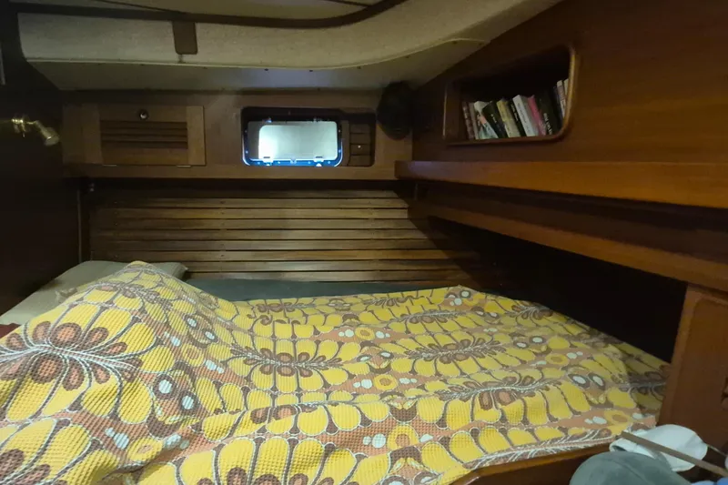  Yacht Photos Pics Cozy cabin interior of 1986 Hallberg-Rassy 49 sailboat with floral bedding and bookshelf.
