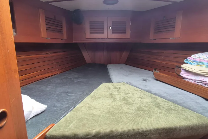  Yacht Photos Pics Cozy cabin interior of 1986 Hallberg-Rassy 49 sailboat with wooden paneling and bedding.
