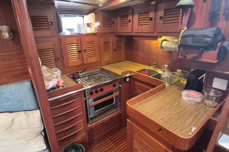  Yacht Photos Pics 1986 Hallberg-Rassy 49 yacht kitchen with wooden cabinetry and compact appliances.