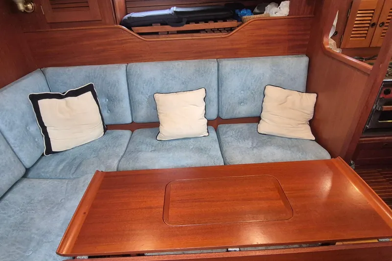  Yacht Photos Pics Interior of 1986 Hallberg-Rassy 49 yacht with blue cushions and wooden table.