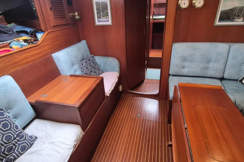  Yacht Photos Pics Interior of 1986 Hallberg-Rassy 49 sailboat with wooden furnishings and blue upholstery.