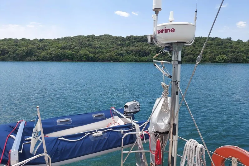  Yacht Photos Pics Sailboat Hallberg-Rassy 49, 1986 model, anchored near lush shoreline with clear blue water.