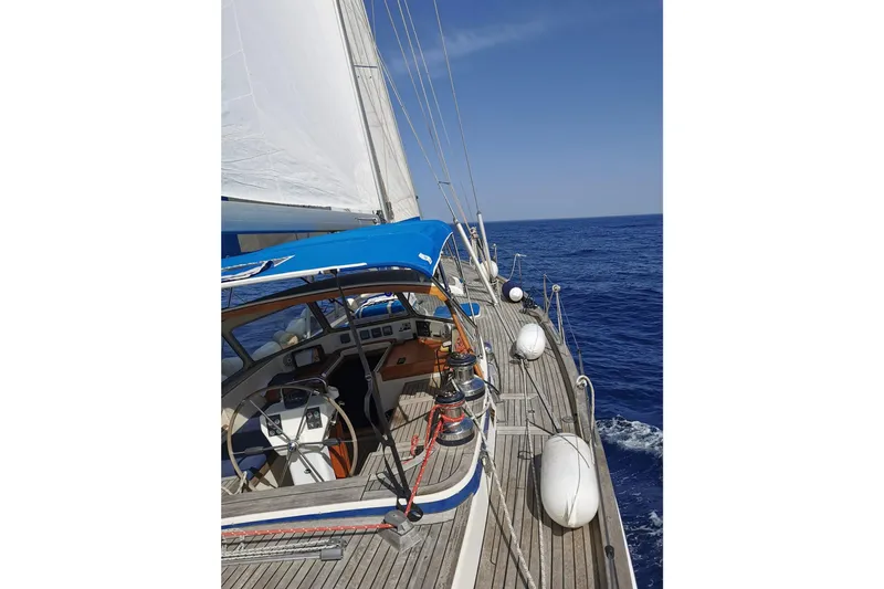  Yacht Photos Pics 1986 Hallberg-Rassy 49 sailboat cruising on open sea with clear blue skies.