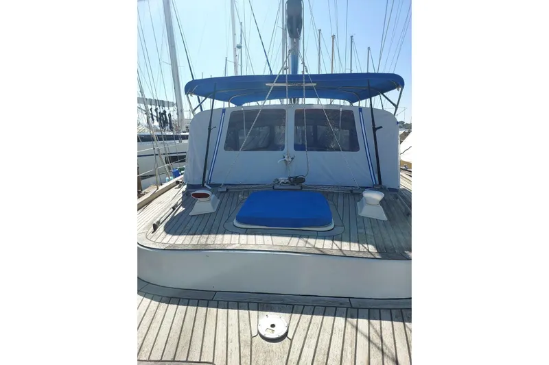  Yacht Photos Pics 1986 Hallberg-Rassy 49 sailboat deck with blue canopy and wooden flooring.