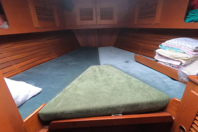  Yacht Photos Pics Cozy cabin interior of 1986 Hallberg-Rassy 49 sailboat with wooden paneling and bedding.