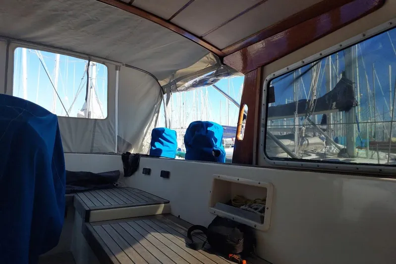  Yacht Photos Pics Interior view of 1986 Hallberg-Rassy 49 sailboat with covered seating and marina backdrop.