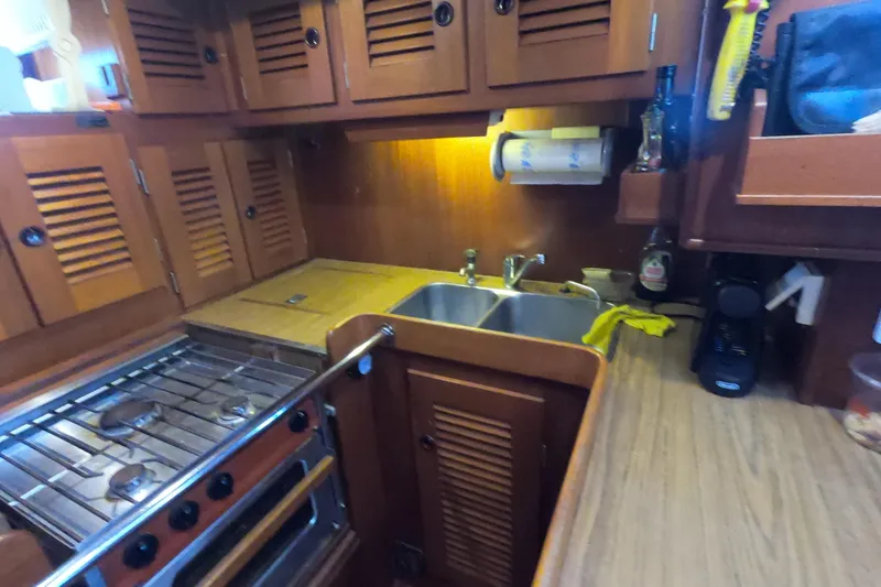  Yacht Photos Pics 1986 Hallberg-Rassy 49 yacht kitchen with wooden cabinets, stove, and double sink.