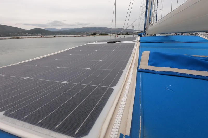  Yacht Photos Pics Sailboat with solar panels on deck, Hallberg-Rassy 49, 1986 model, docked by the shore.