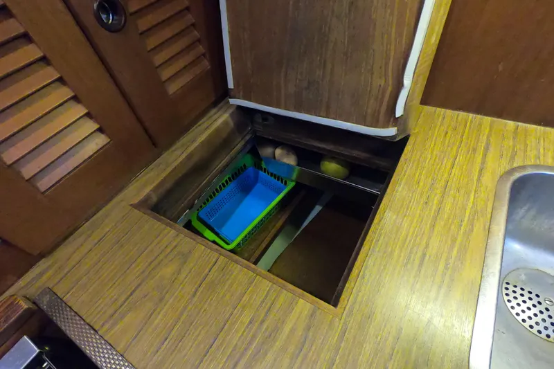  Yacht Photos Pics Galley storage area in 1986 Hallberg-Rassy 49 sailboat with wooden finish and sink.