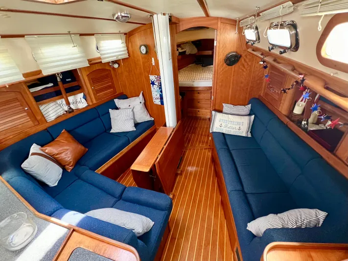 Vela Dare II Yacht Photos Pics Interior of a 1999 Sabre 402 sailboat with blue seating and wooden finishes.