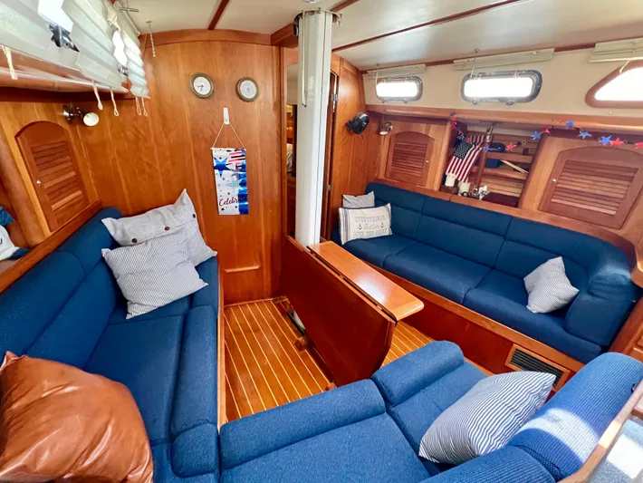 Vela Dare II Yacht Photos Pics 1999 Sabre 402 sailboat interior with blue seating, wooden paneling, and nautical decor.