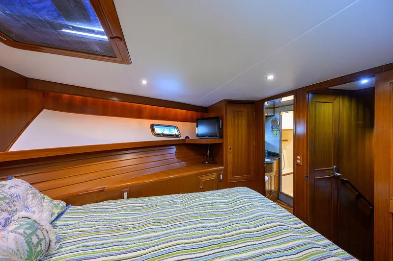 Change Of Latitude Yacht Photos Pics Luxurious cabin interior of 2001 Ocean Alexander 602 yacht with wood paneling and cozy bedding.