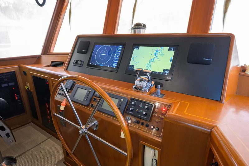 Change Of Latitude Yacht Photos Pics Cockpit of 2001 Ocean Alexander 602 yacht with navigation screens and wooden steering wheel.