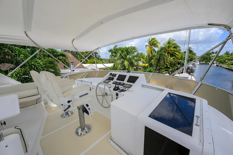 Change Of Latitude Yacht Photos Pics Flybridge of 2001 Ocean Alexander 602 yacht with helm station and seating, surrounded by tropical scenery.