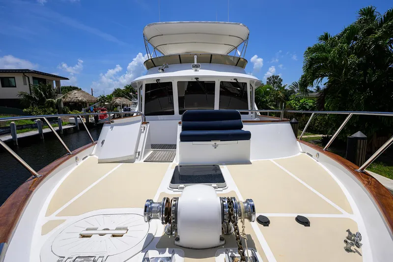 Change Of Latitude Yacht Photos Pics 2001 Ocean Alexander 602 yacht deck with seating, docked near lush greenery and blue sky.
