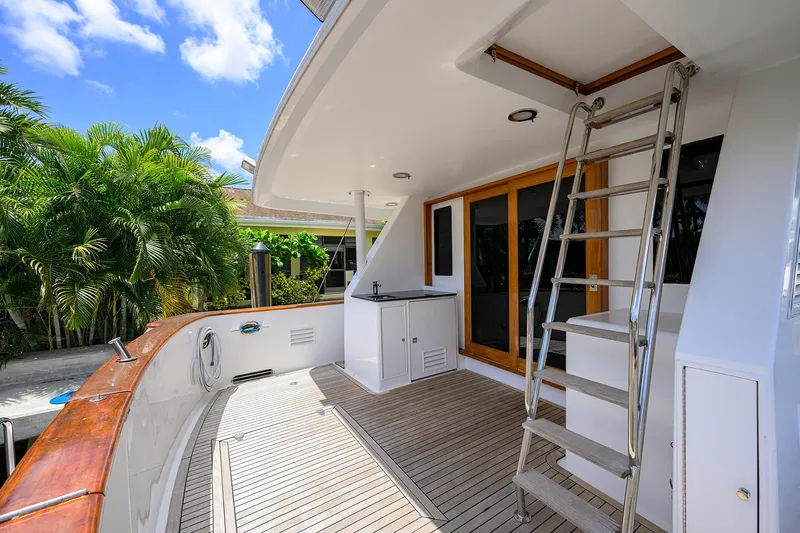 Change Of Latitude Yacht Photos Pics Ocean Alexander 602 yacht deck with ladder, wooden flooring, and lush greenery, 2001 model.