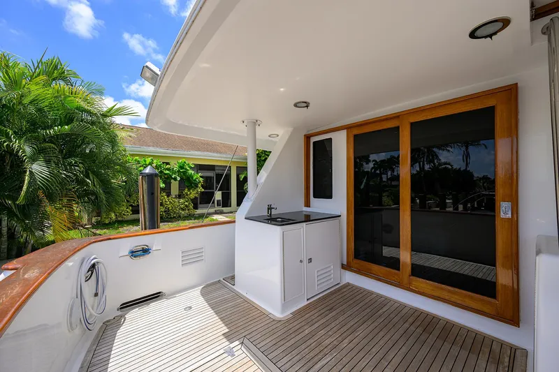 Change Of Latitude Yacht Photos Pics Outdoor deck of 2001 Ocean Alexander 602 yacht with wooden flooring and sliding glass doors.