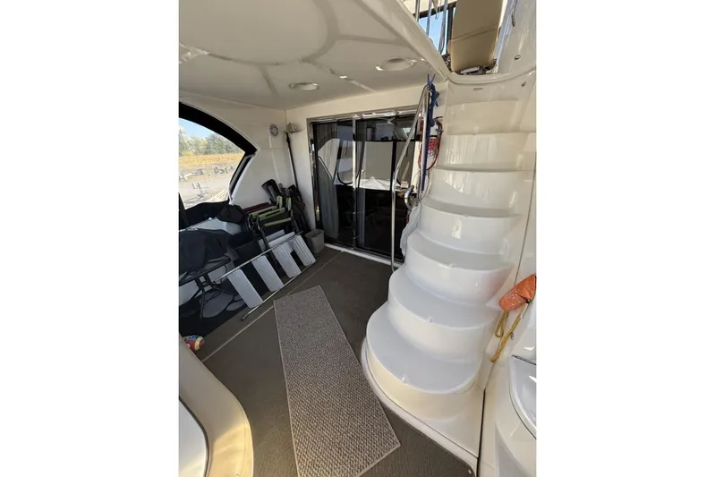 Bad Boy VI Yacht Photos Pics Interior view of 2016 Meridian 441 Sedan yacht with curved staircase and seating area.