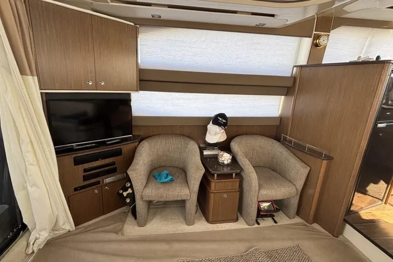 Bad Boy VI Yacht Photos Pics Interior of 2016 Meridian 441 Sedan with TV, chairs, and wooden cabinetry.