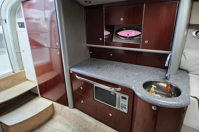 Reduced! Yacht Photos Pics 2005 Formula 400 Super Sport yacht interior with kitchenette, featuring wood cabinets and a compact sink.