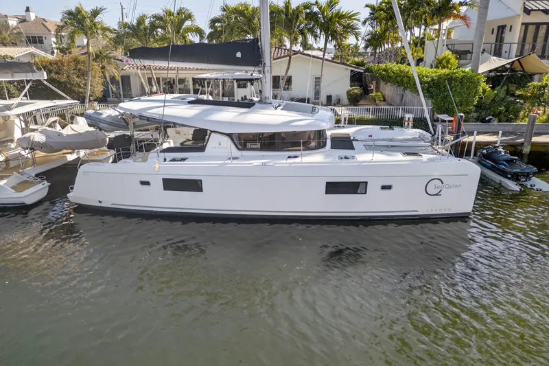 Seaquinn Yacht Photos Pics 2019 Lagoon 42 catamaran docked near palm trees and waterfront homes.