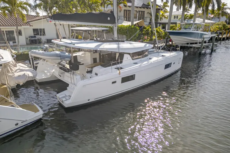 Seaquinn Yacht Photos Pics 2019 Lagoon 42 catamaran docked in a sunny marina, surrounded by palm trees.