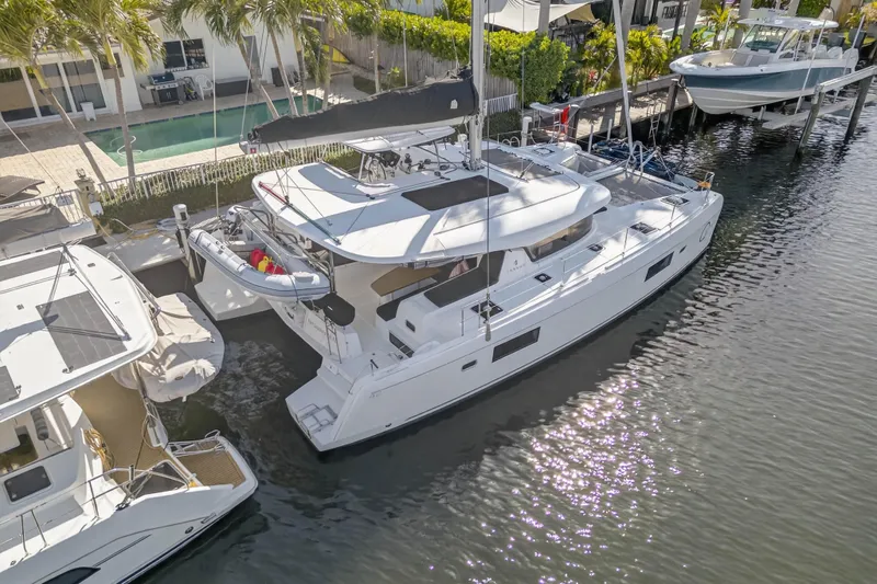 Seaquinn Yacht Photos Pics 2019 Lagoon 42 catamaran docked by waterfront homes, surrounded by palm trees.