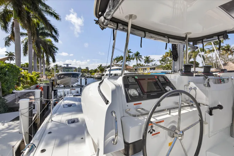 Seaquinn Yacht Photos Pics 2019 Lagoon 42 catamaran docked, featuring steering wheel and navigation controls, surrounded by palm trees.