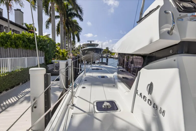 Seaquinn Yacht Photos Pics 2019 Lagoon 42 catamaran docked by palm trees, sunny marina view.