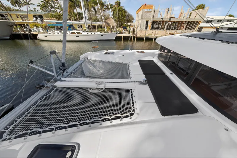 Seaquinn Yacht Photos Pics 2019 Lagoon 42 catamaran docked, featuring spacious deck and netting, with waterfront view.