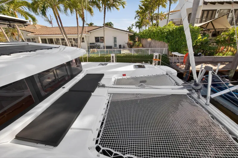 Seaquinn Yacht Photos Pics 2019 Lagoon 42 catamaran with netted deck, docked near tropical house.