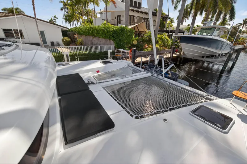 Seaquinn Yacht Photos Pics 2019 Lagoon 42 catamaran docked by waterfront homes, featuring spacious deck and netting.