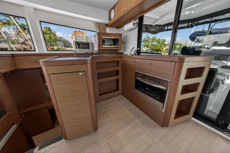 Seaquinn Yacht Photos Pics Modern kitchen interior of 2019 Lagoon 42 catamaran with wood finish and appliances.