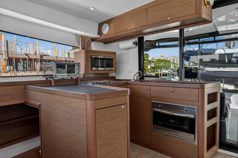 Seaquinn Yacht Photos Pics Modern kitchen interior of 2019 Lagoon 42 yacht with wood cabinetry and appliances.