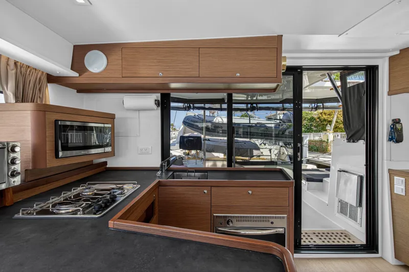 Seaquinn Yacht Photos Pics Modern kitchen interior of 2019 Lagoon 42 yacht with stove, oven, and outdoor view.