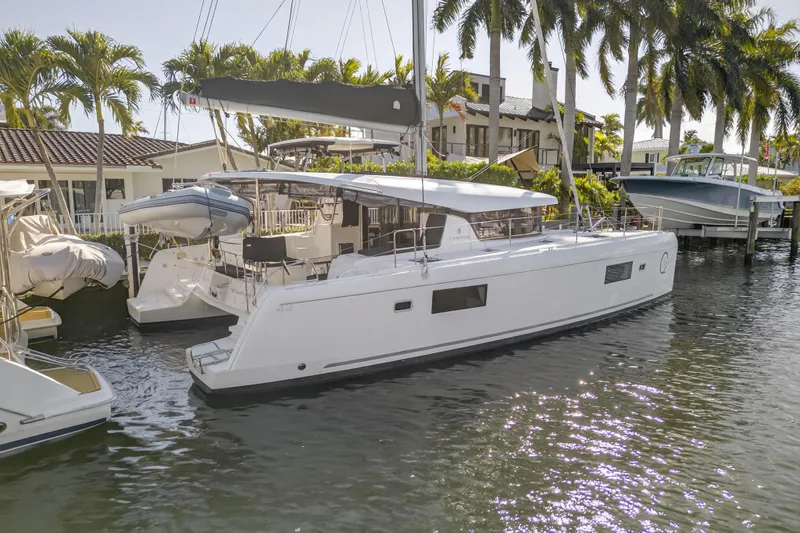 Seaquinn Yacht Photos Pics 2019 Lagoon 42 catamaran docked by palm trees, reflecting on calm water.