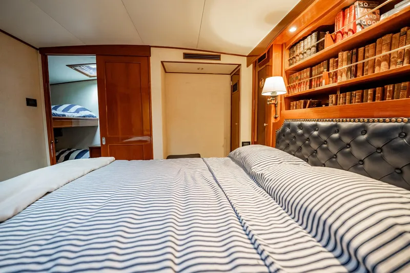Lucky Yacht Photos Pics Luxurious cabin interior of 1983 Rybovich 55 Convertible yacht with striped bedding and bookshelf.