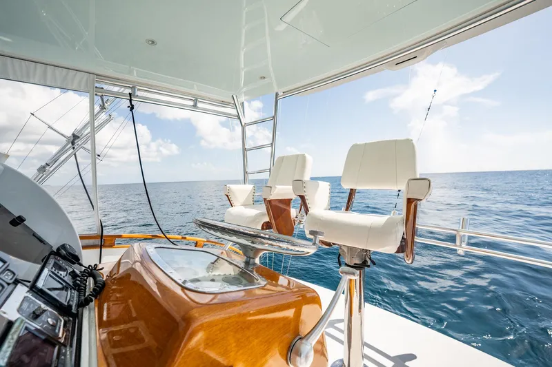 Lucky Yacht Photos Pics 1983 Rybovich 55 Convertible yacht interior with ocean view, featuring white chairs and wooden accents.