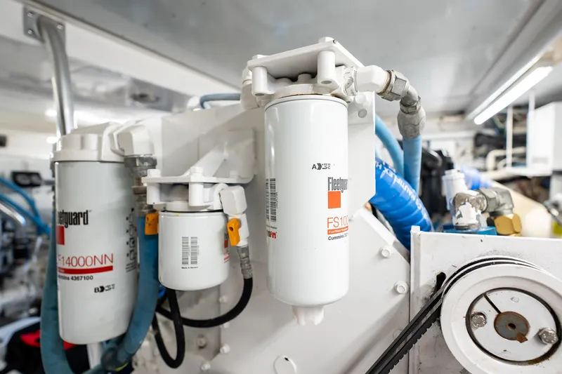Lucky Yacht Photos Pics Engine room of 1983 Rybovich 55 Convertible, featuring Fleetguard filters and blue hoses.