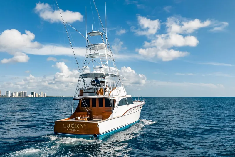 Lucky Yacht Photos Pics 1983 Rybovich 55 Convertible yacht cruising on open sea under blue sky.