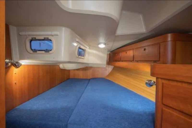 Blue Sky Yacht Photos Pics Interior cabin of 2000 Sabre 402 sailboat with wooden finish and blue bedding.